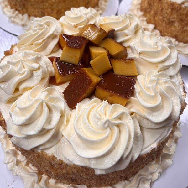 Filipino cake with white frosting swirls and topped with cubes of leche flan.