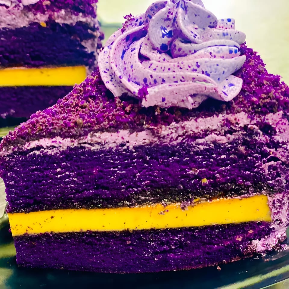 Close-up of a vibrant purple ube cake slice with a bright yellow custard layer and purple frosting.