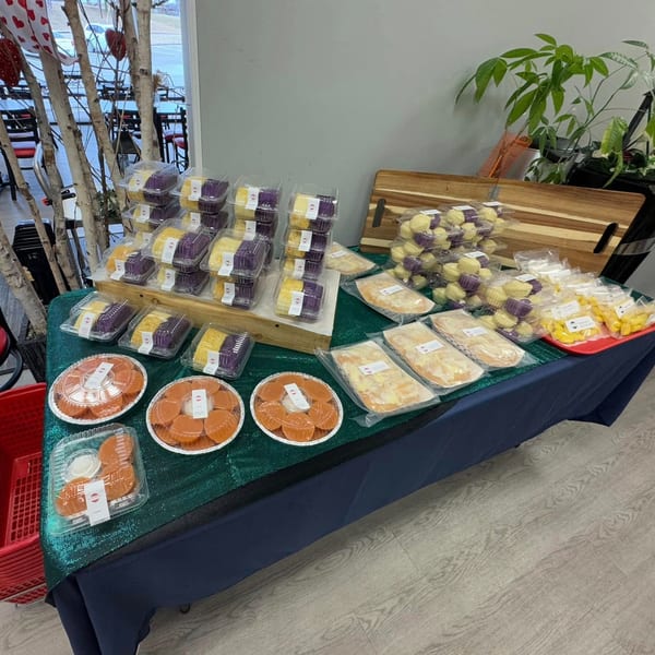 A table laden with various packaged Filipino baked goods, including purple and yellow cakes, and orange pastries.
