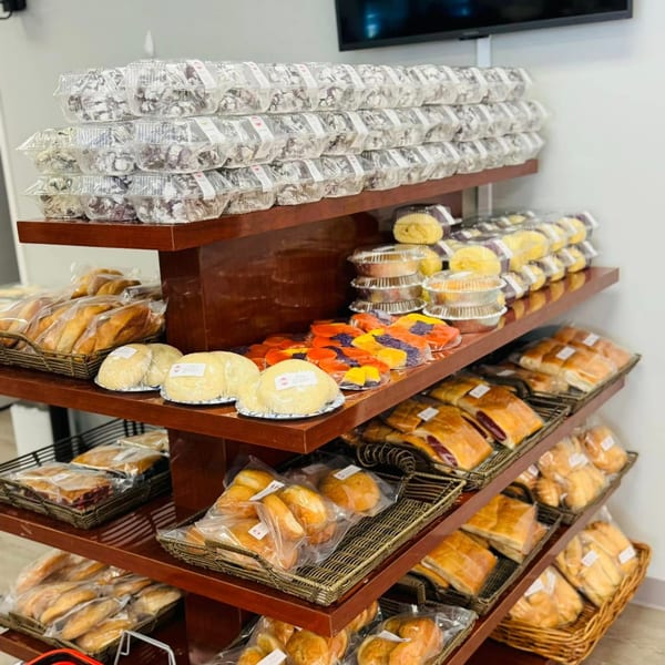 A multi-tiered wooden display shelf filled with various packaged Filipino baked goods and pastries.