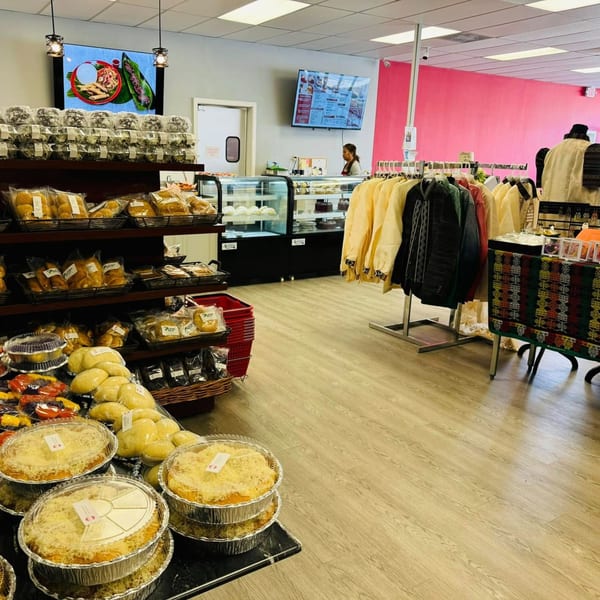 Interior of Filipino Bakery Cafe & Market with baked goods, clothing, and a staff member at the counter.