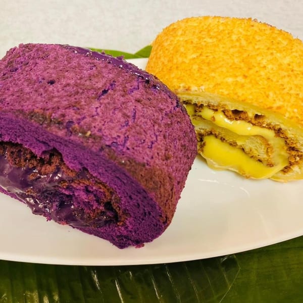 Close-up of a purple ube roll and a golden mamon roll, both sliced to show creamy fillings.