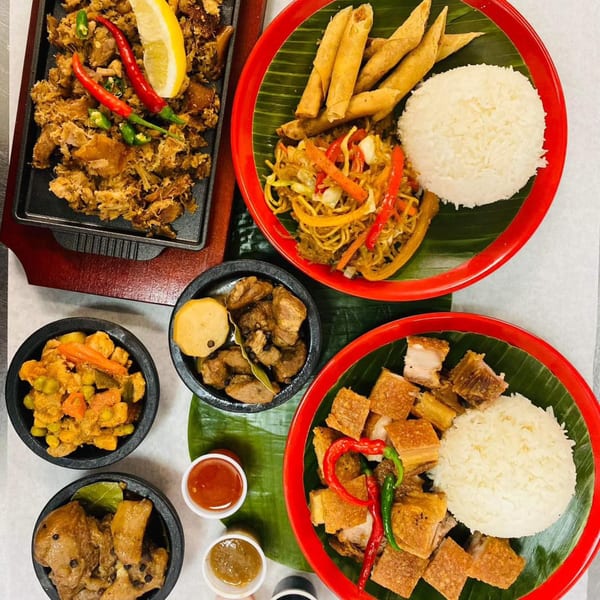 Overhead view of various Filipino dishes, including sisig, pancit, lumpia, lechon kawali, and adobo.
