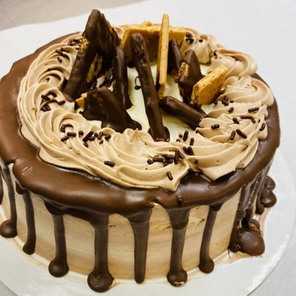A chocolate cake with chocolate ganache drips, coffee-flavored frosting swirls, chocolate sticks, and honeycomb candy.