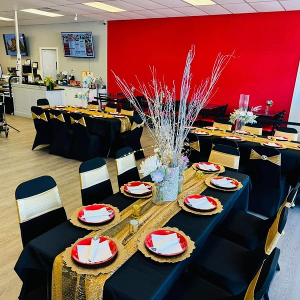 Filipino Bakery Cafe & Market dining area set with black and gold tables, red plates, and white floral centerpieces.