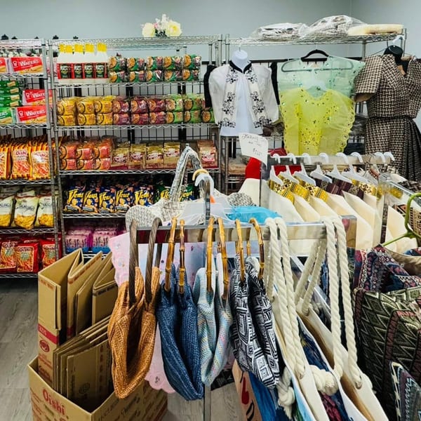 A Filipino bakery and market with shelves of snacks, clothing, and bags for sale.